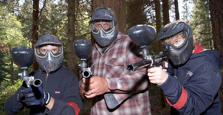 Location photography of father and son man camp showing paintball gear and guns
