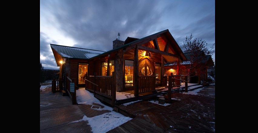Architectural photography of high mountain lodge in Montana with snow on the roof and warm glowing lights
